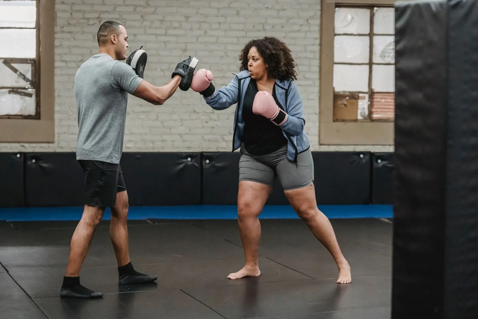 Anjana in boxing gloves hitting pads held by her trainer