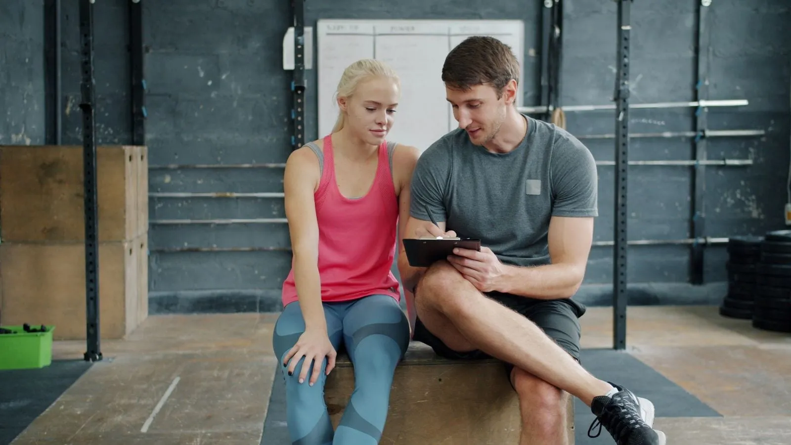 Trainer reviewing progress on a tablet with a member