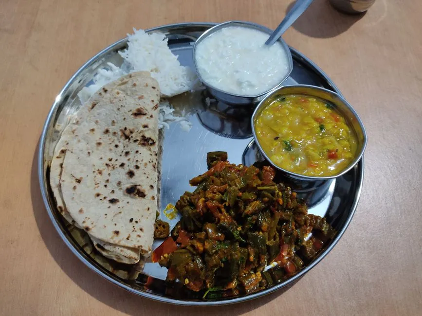 A vegetarian thali with roti, rice, dal, okra and a bowl of curd