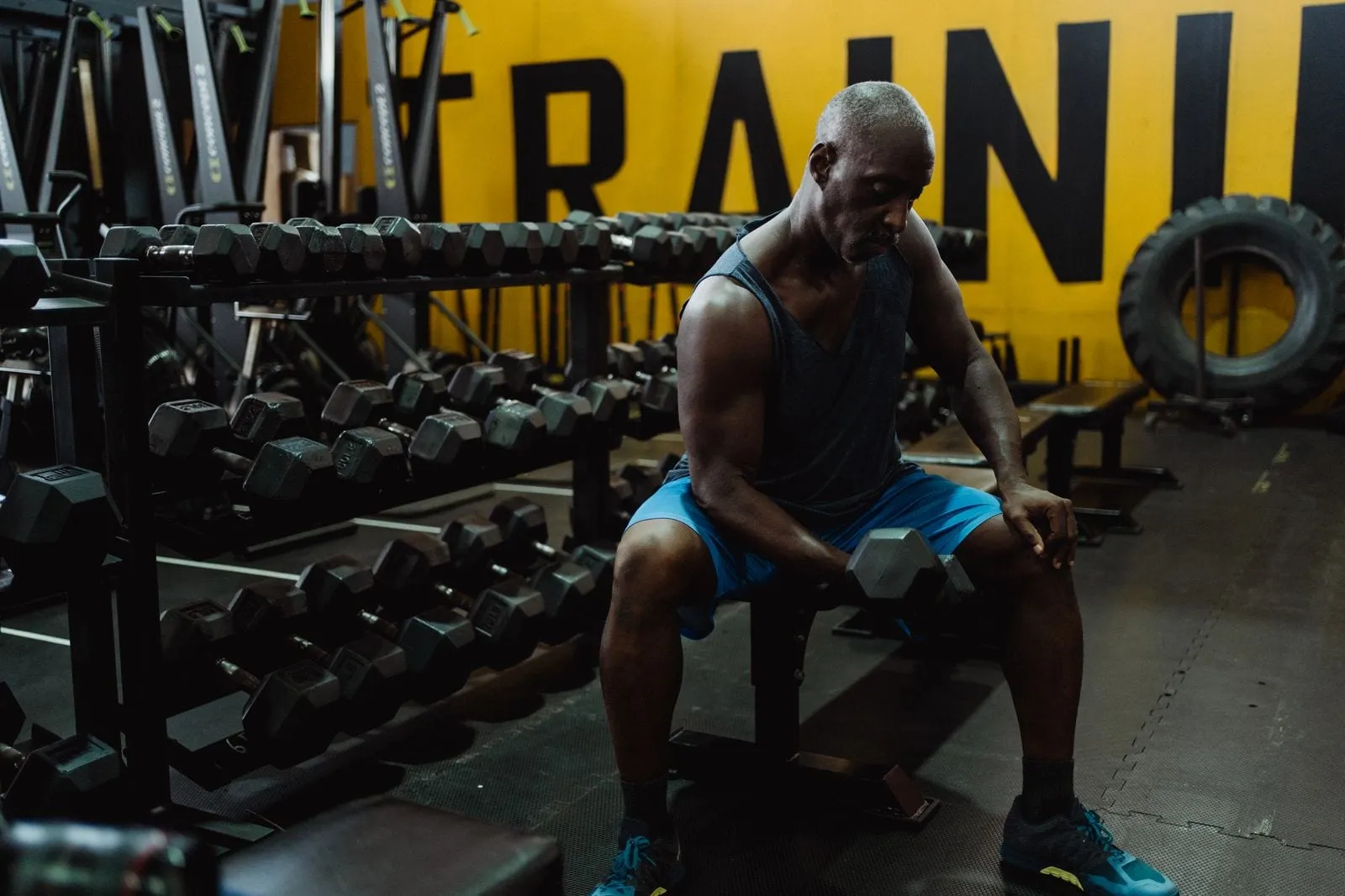 Krishna sitting on a bench with dumbbells, between sets
