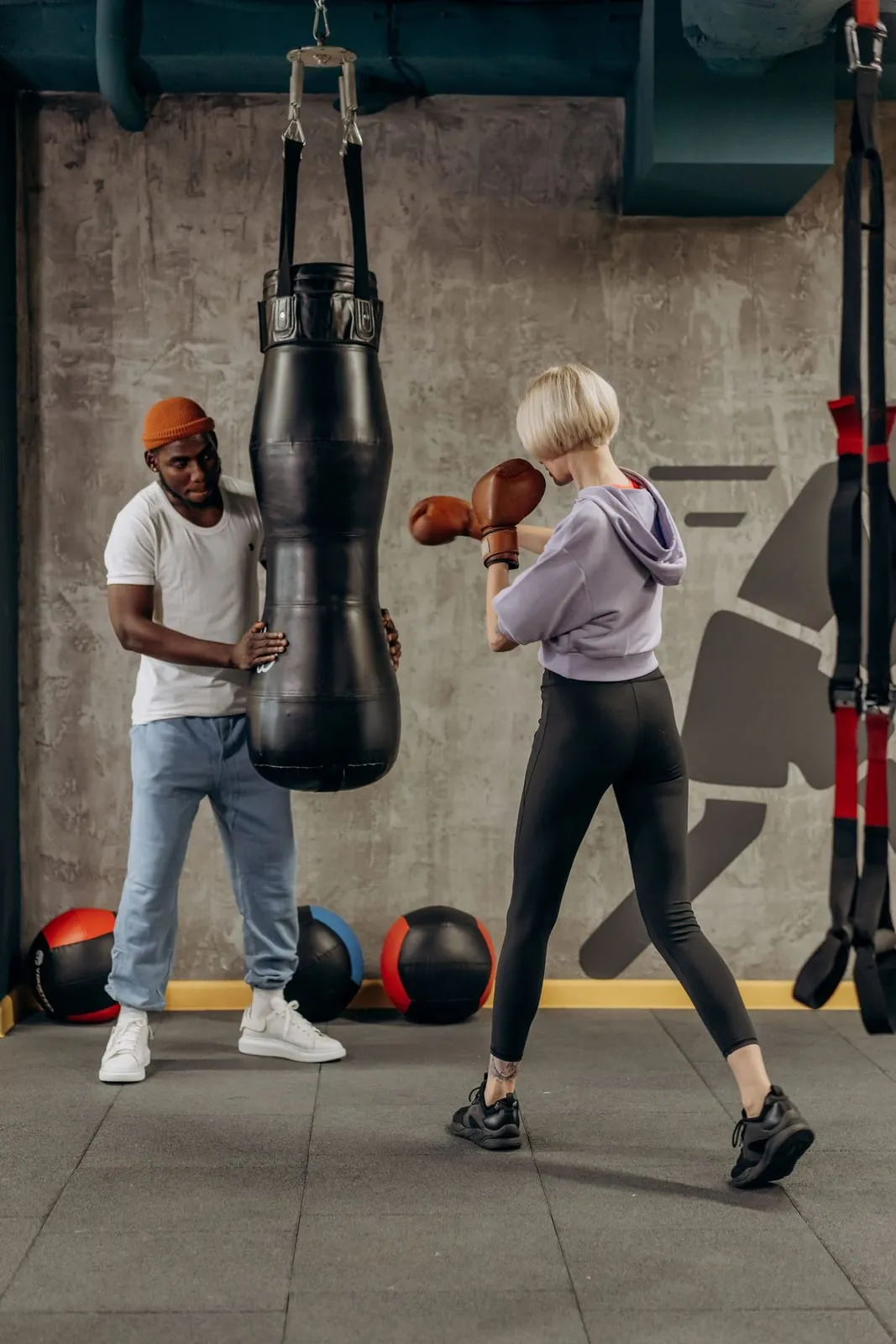 Lena punching a heavy bag while her coach holds it