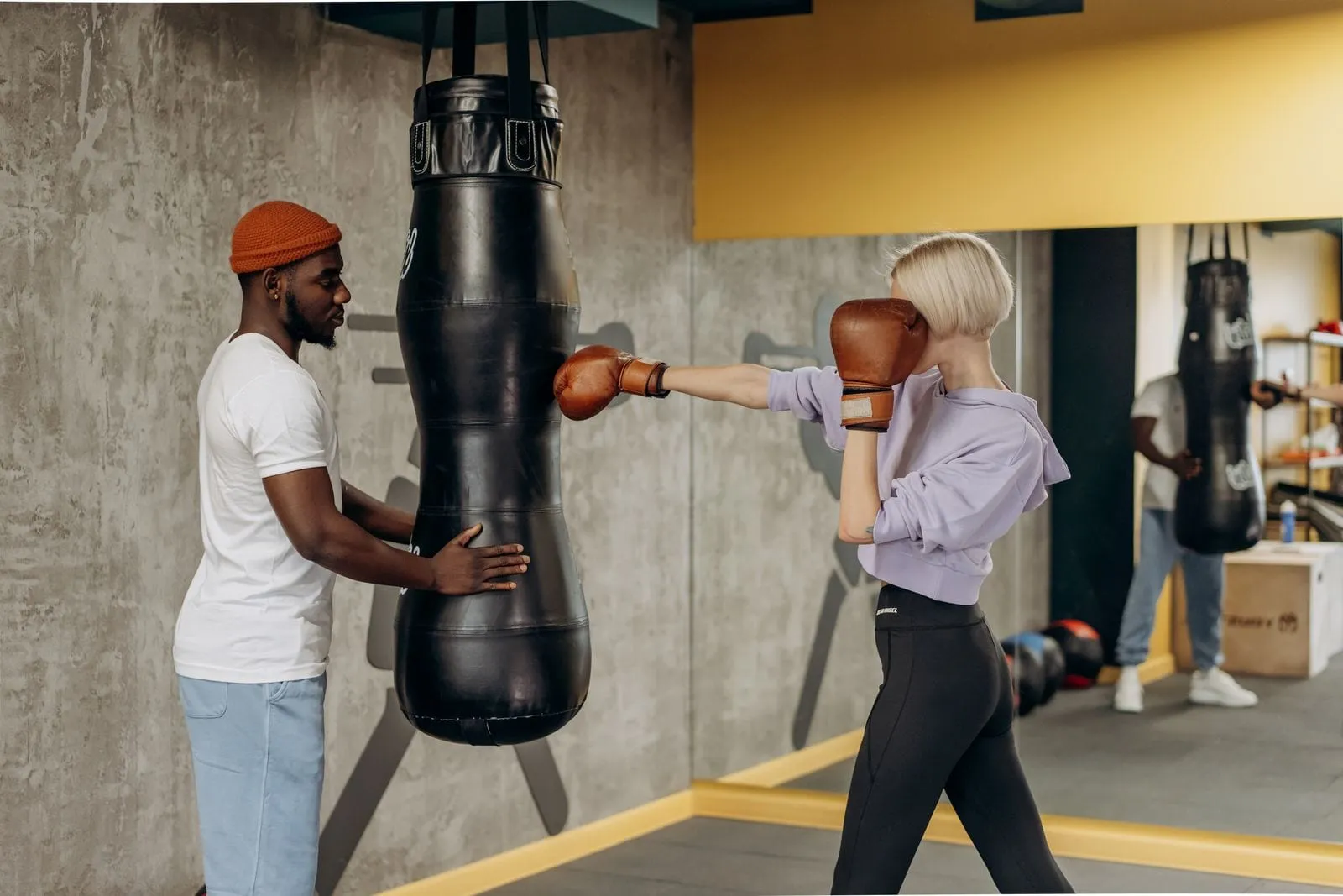 Lena hitting the heavy bag with her coach steadying it