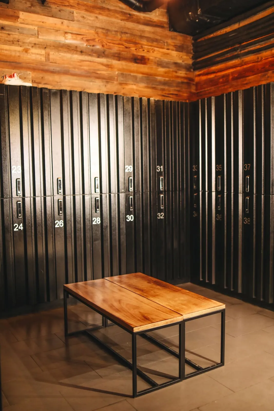 Black lockers and a wooden bench under a warm timber ceiling