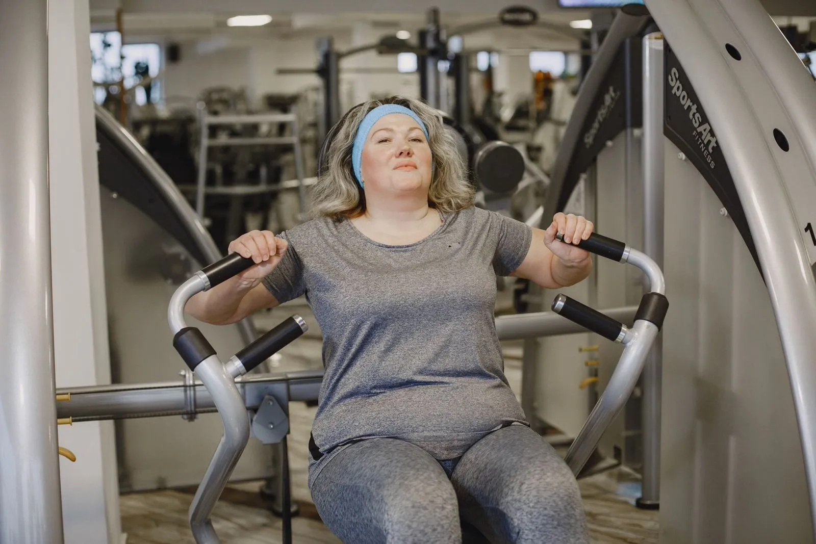 Maya smiling on a chest press machine in the gym