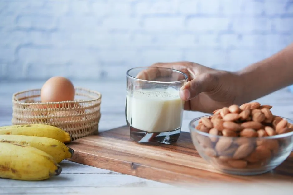 A glass of milk with almonds, a banana and an egg on a wooden board