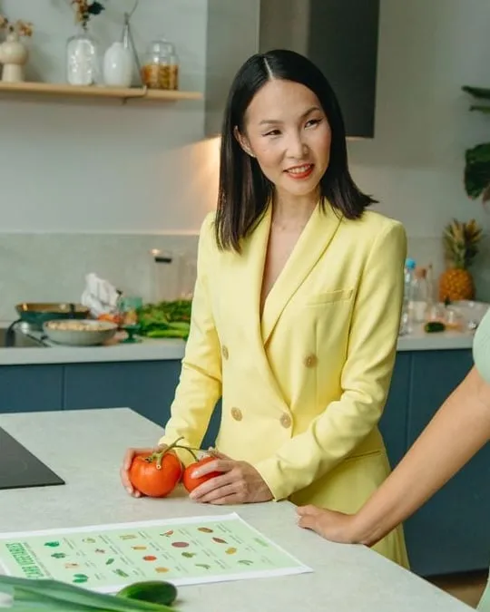 Nutrition coach Ritu Maharjan holding fresh tomatoes in a kitchen