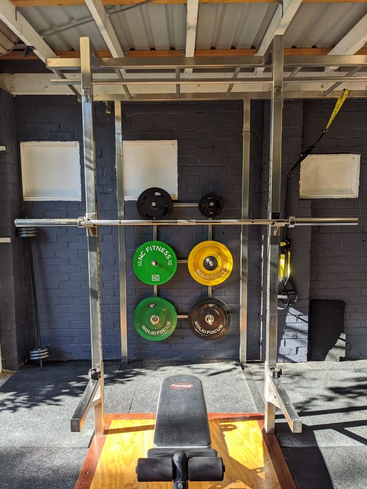 Squat rack on a wooden platform with coloured bumper plates