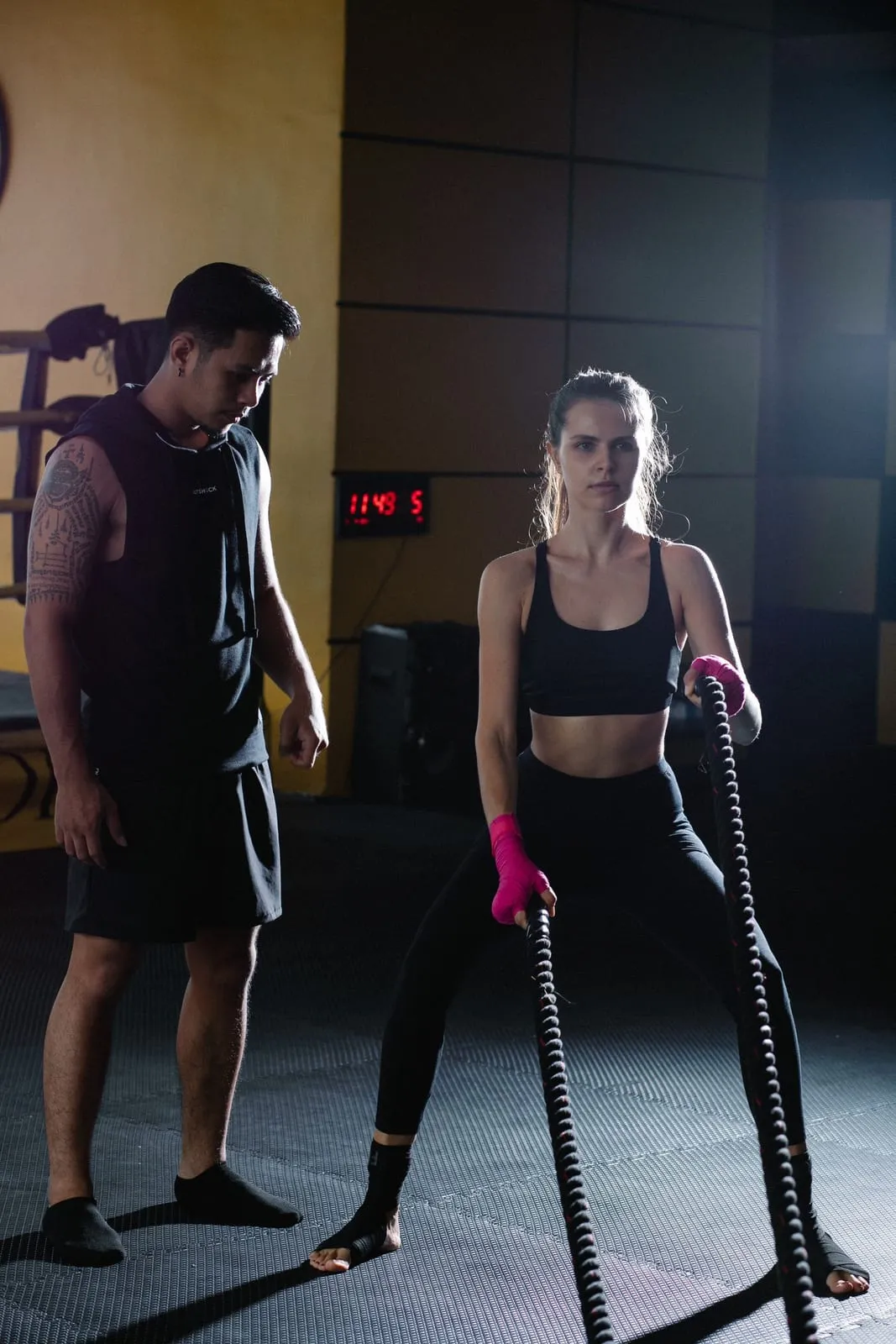 Priya working battle ropes while her coach times the round