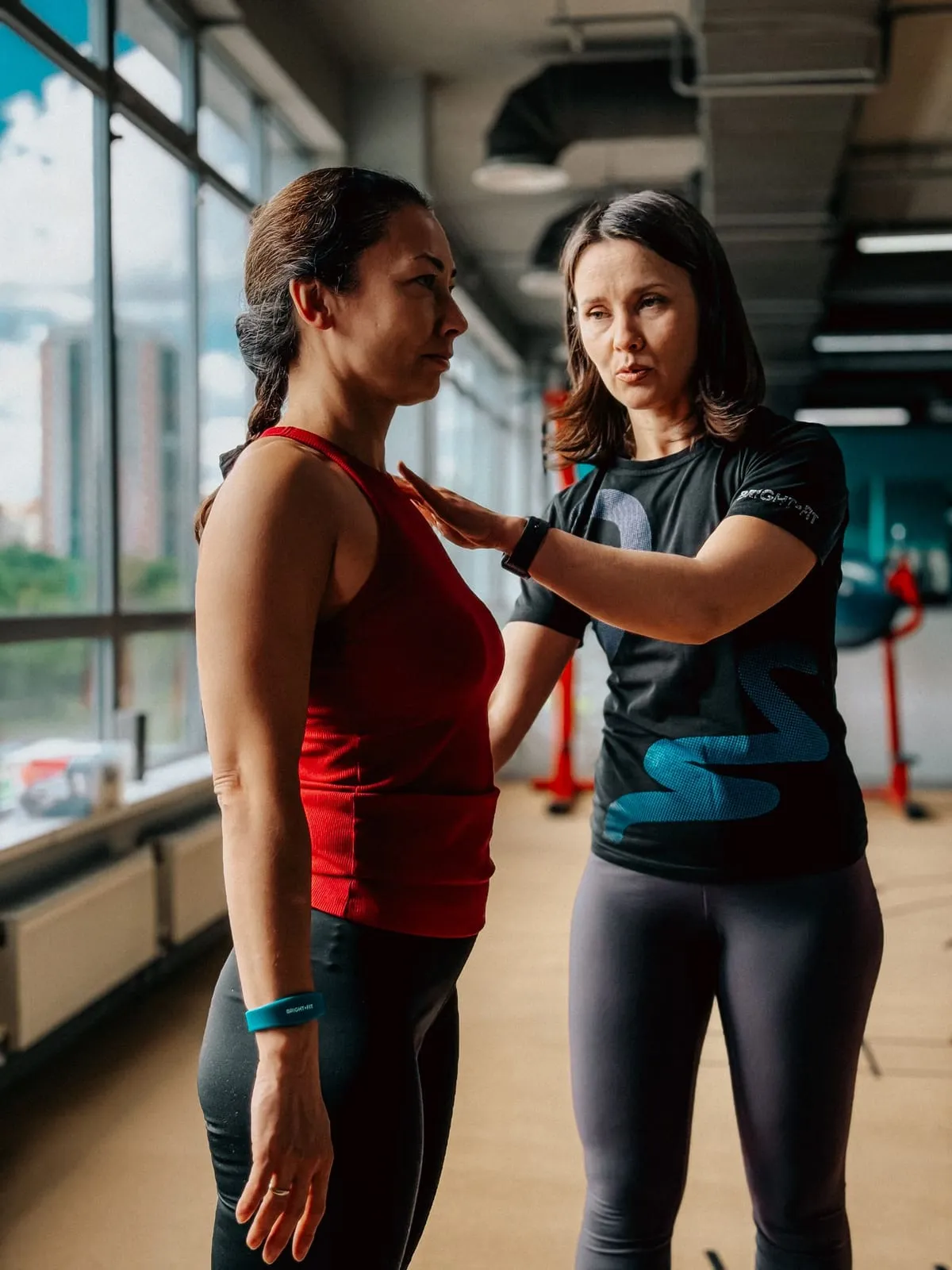 Trainer guiding a man through a dumbbell exercise on the gym floor