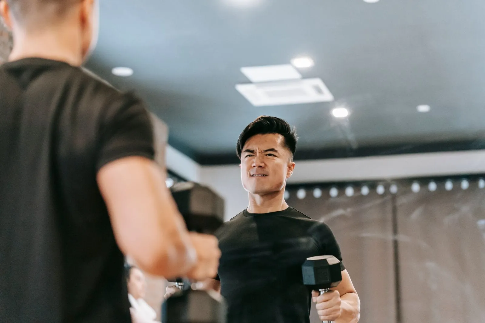 Rohan lifting dumbbells in front of the mirror on his first morning