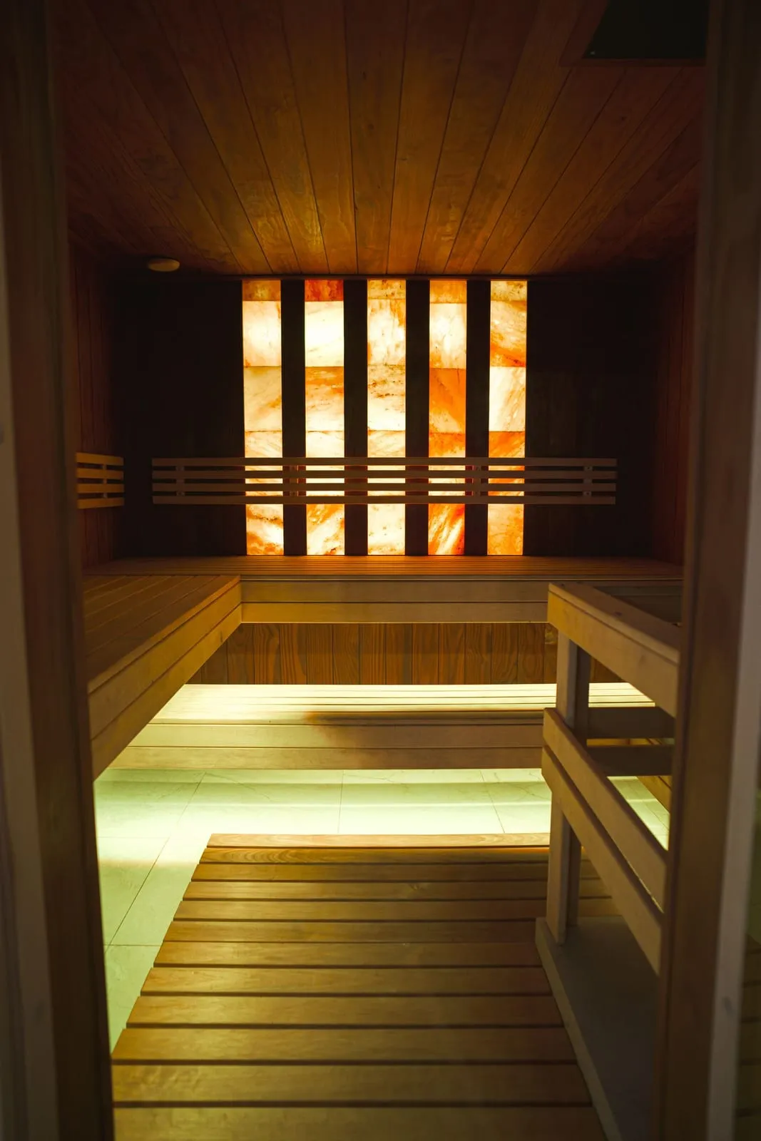 Glowing salt-brick wall above warm wooden steam room benches
