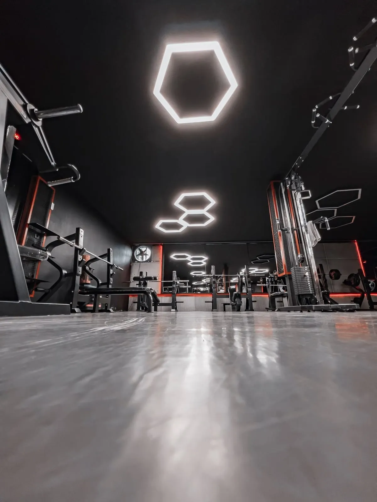 Dark strength floor with machines and racks under hexagon ceiling lights