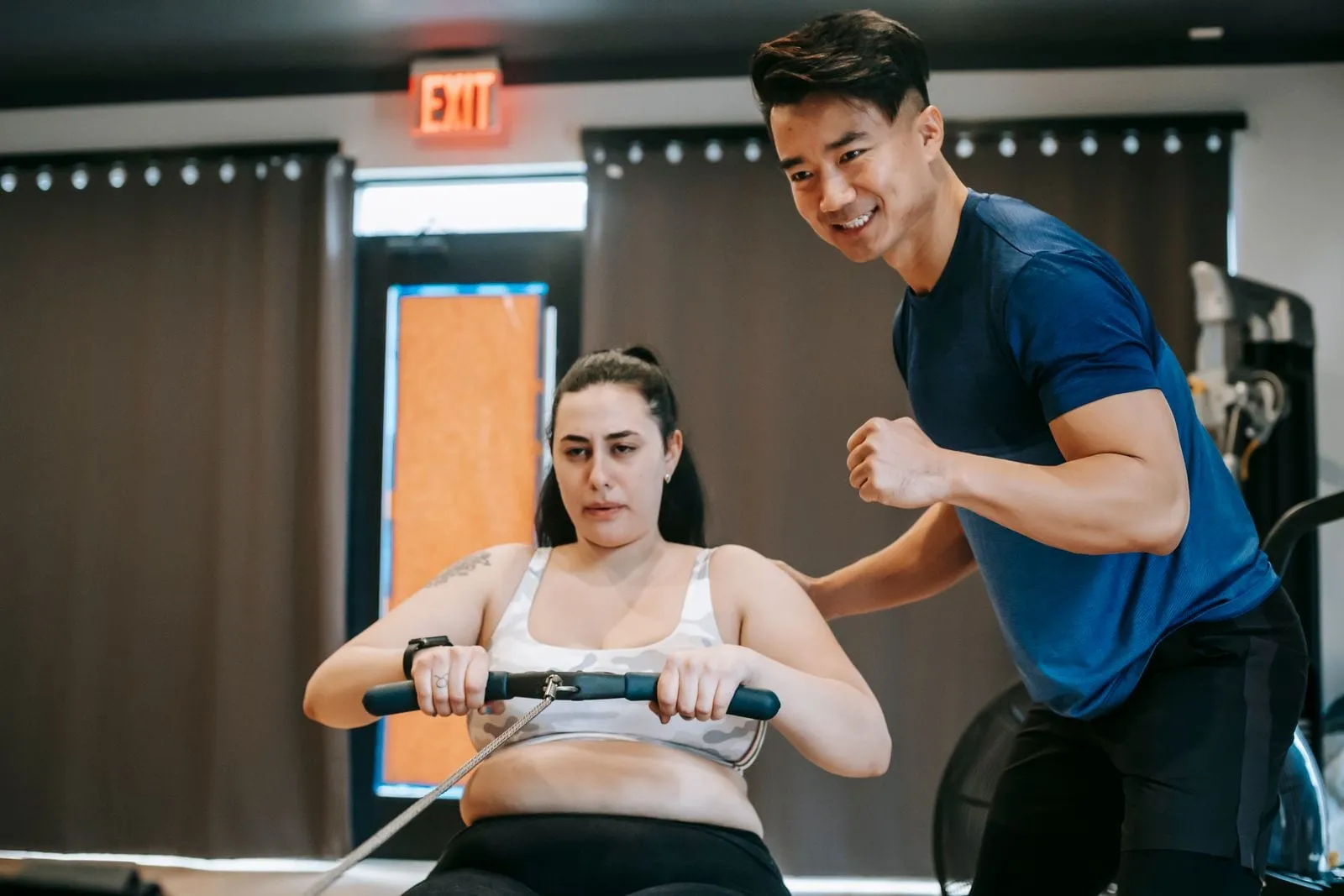 Sunita on the rowing machine while her trainer encourages her