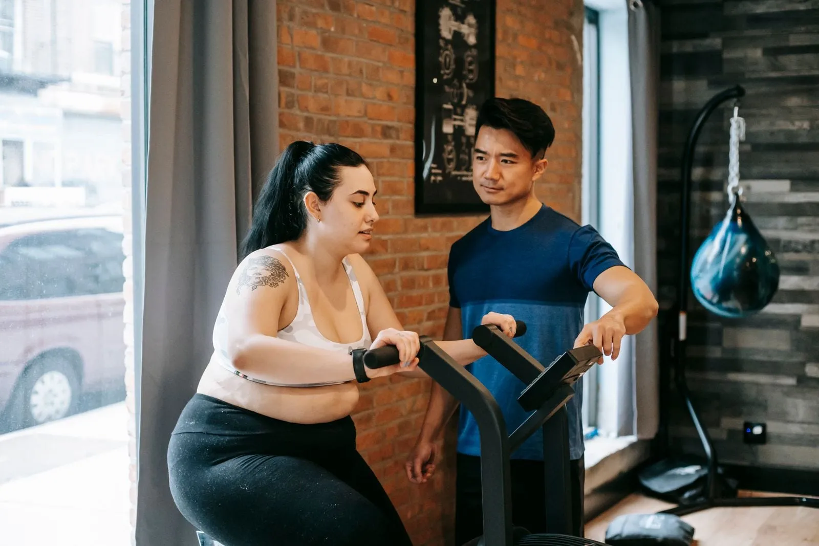 Sunita on an exercise bike with her trainer beside her
