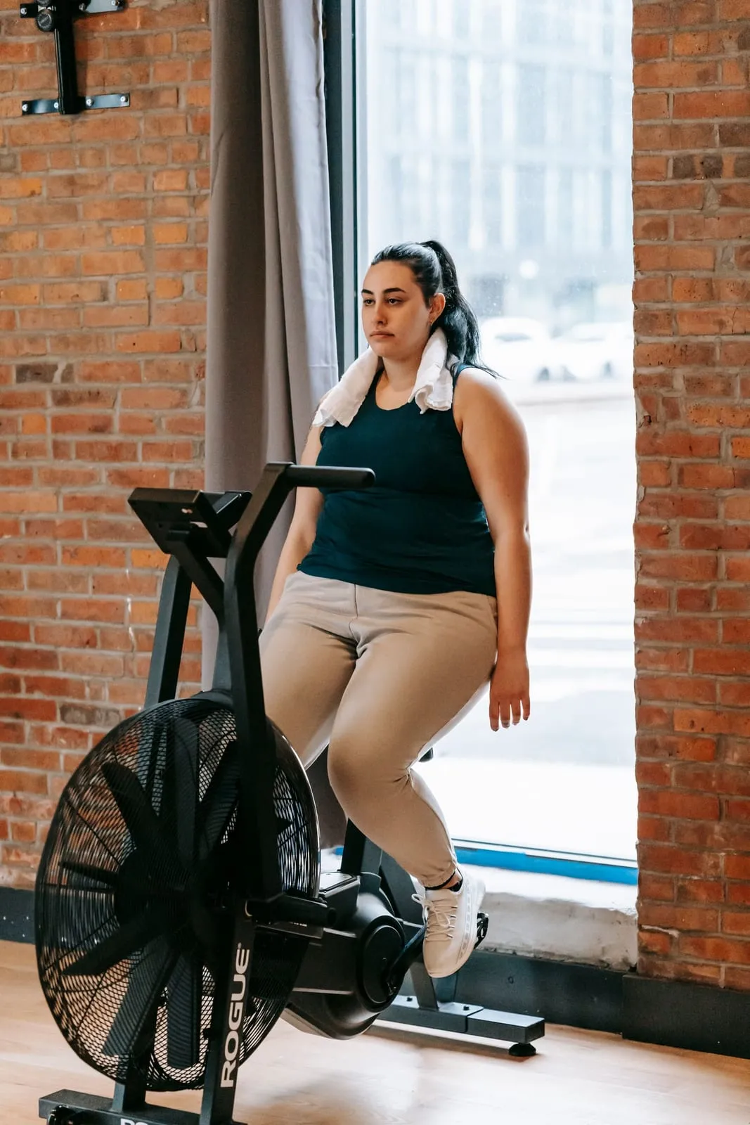 Sunita on an air bike by the window, a towel round her neck