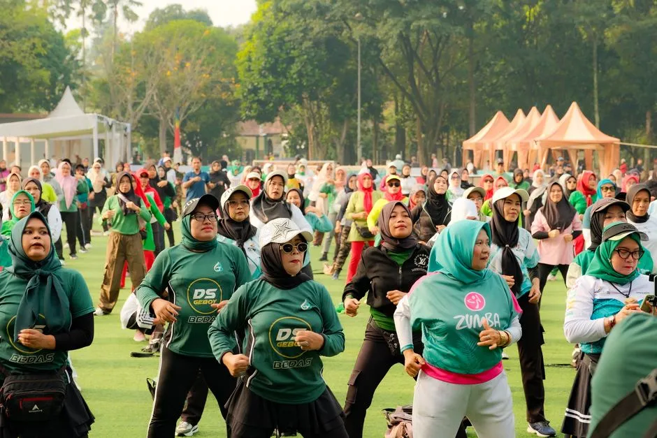 A large group of women following an instructor in an outdoor Zumba dance class